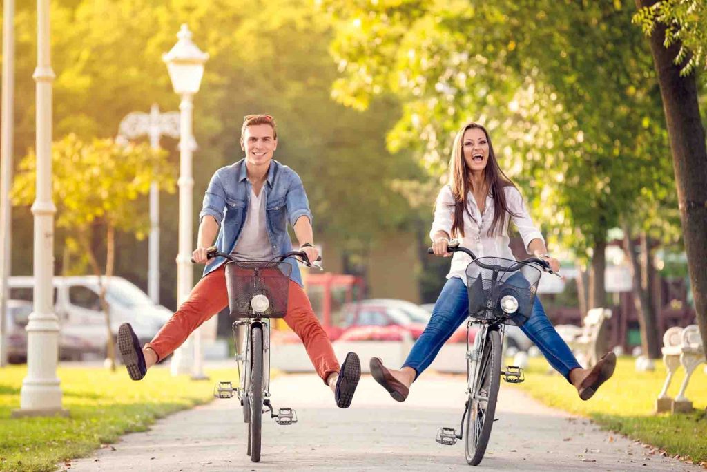 Happy funny couple riding on bicycle